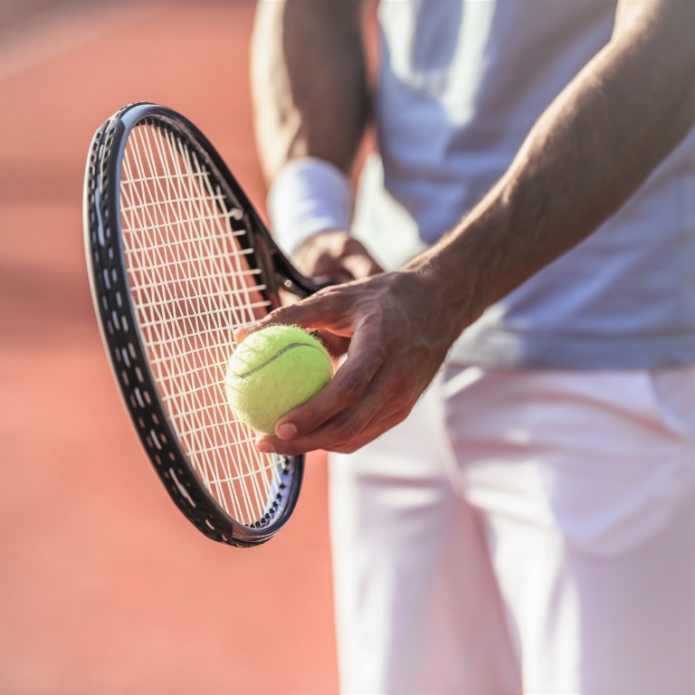 Cropped image of handsome man playing tennis on tennis court outdoors