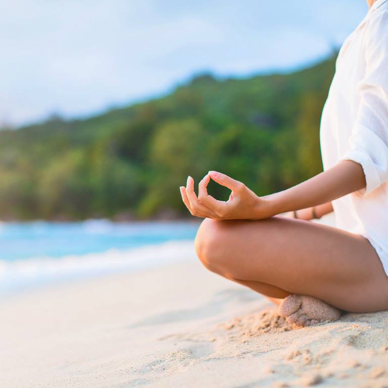 Closeup of Woman's Practicing Lotus Pose on the Beach at Sunset